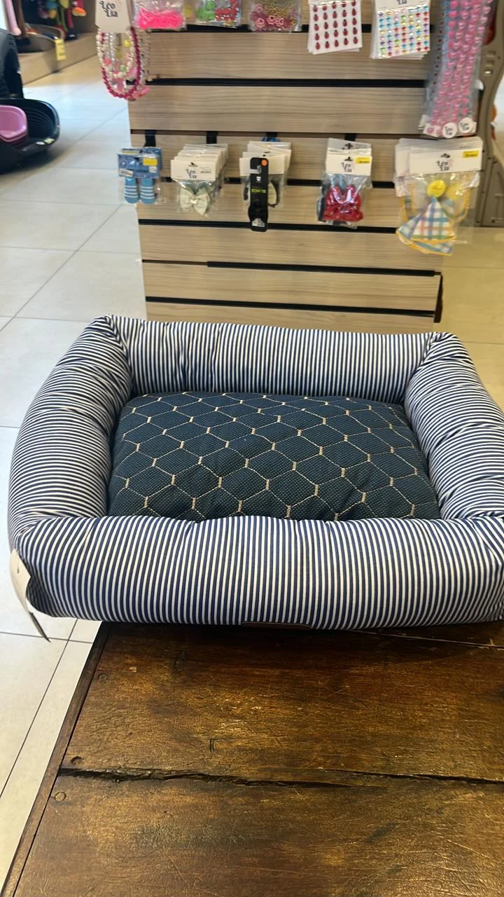 Foto real do protetor azul sobre a almofada de uma cama pet listrada
